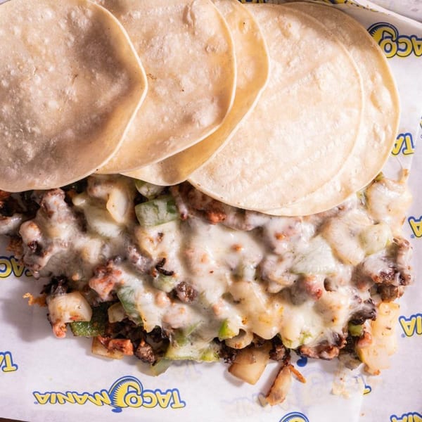 TacoMania's cheesy taco filling with meat, onions, and peppers, topped with warm tortillas.